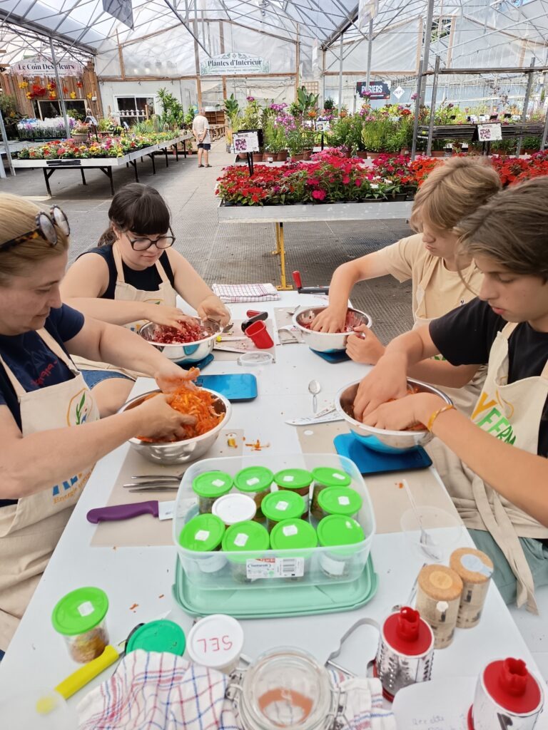 Participants mélangeant des légumes dans un saladier avec du sel et des épices lors d'un atelier de lactofermentation à St léonard , atelier animé par alyferm le 16 juillet 2026